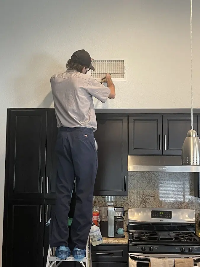 Technician inspecting an air vent during HVAC service in Tavares